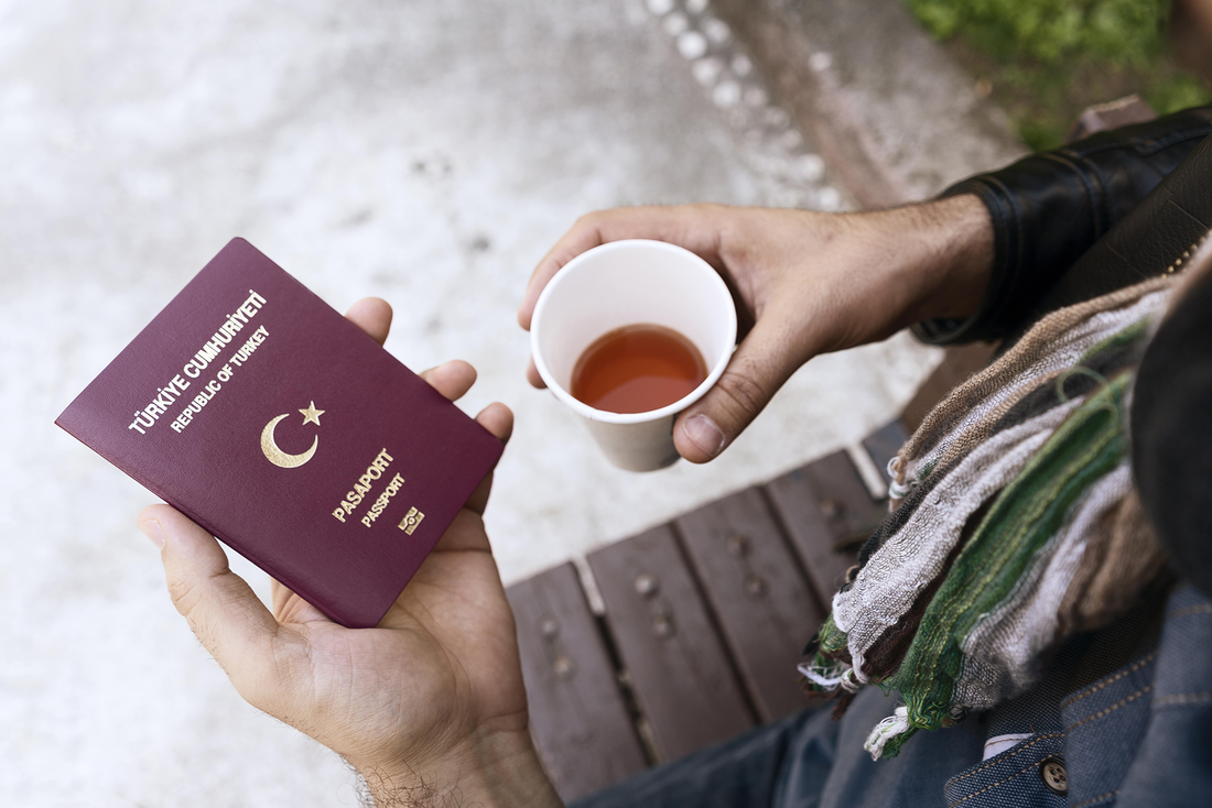 Mensch hält einen türkischen Reisepass und Tee in den Händen - b24 Ratgeber Türkische Geburtsurkunde übersetzen