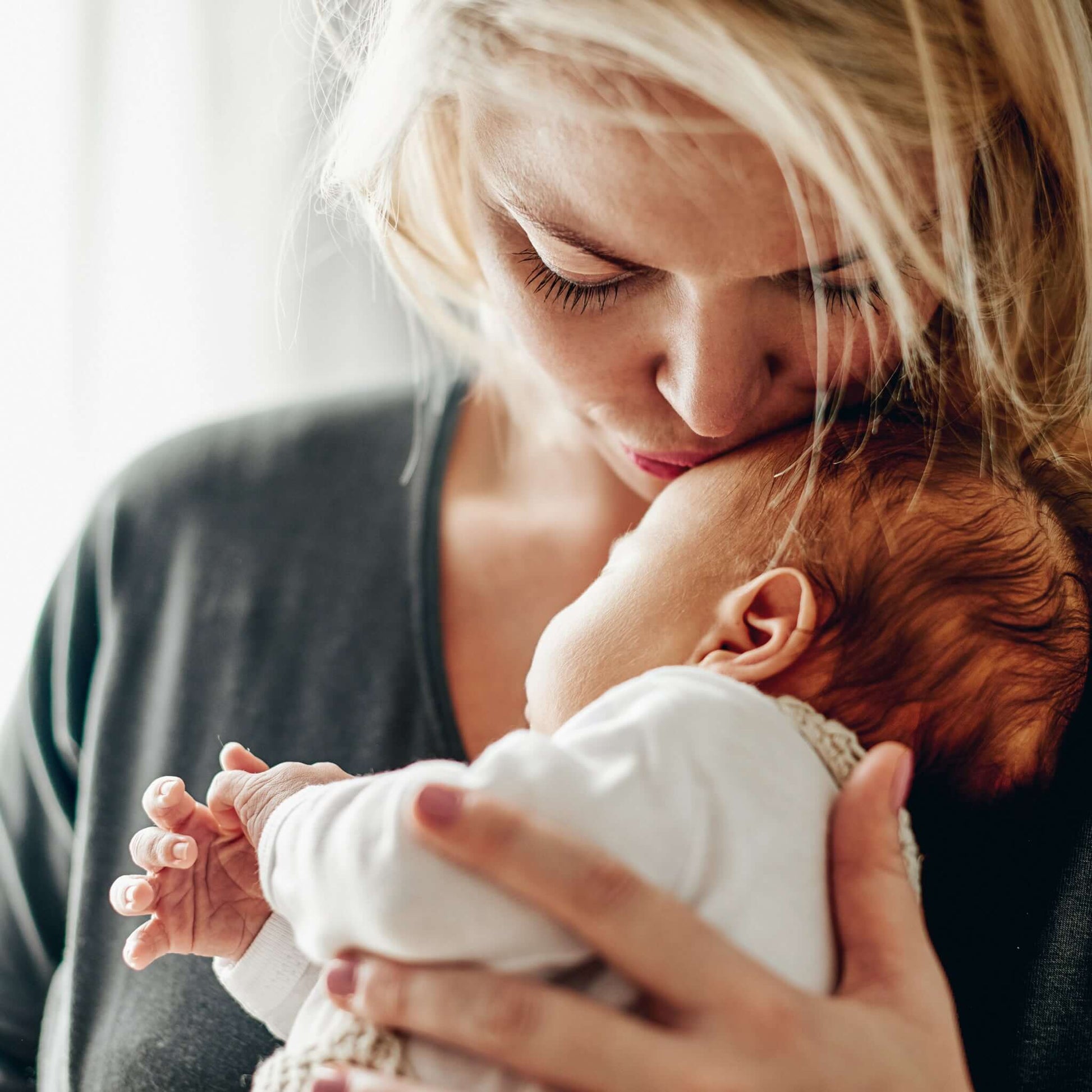 Geburtsurkunde übersetzen lassen: Eine Mutter gibt ihrem Baby einen Kuss auf die Stirn