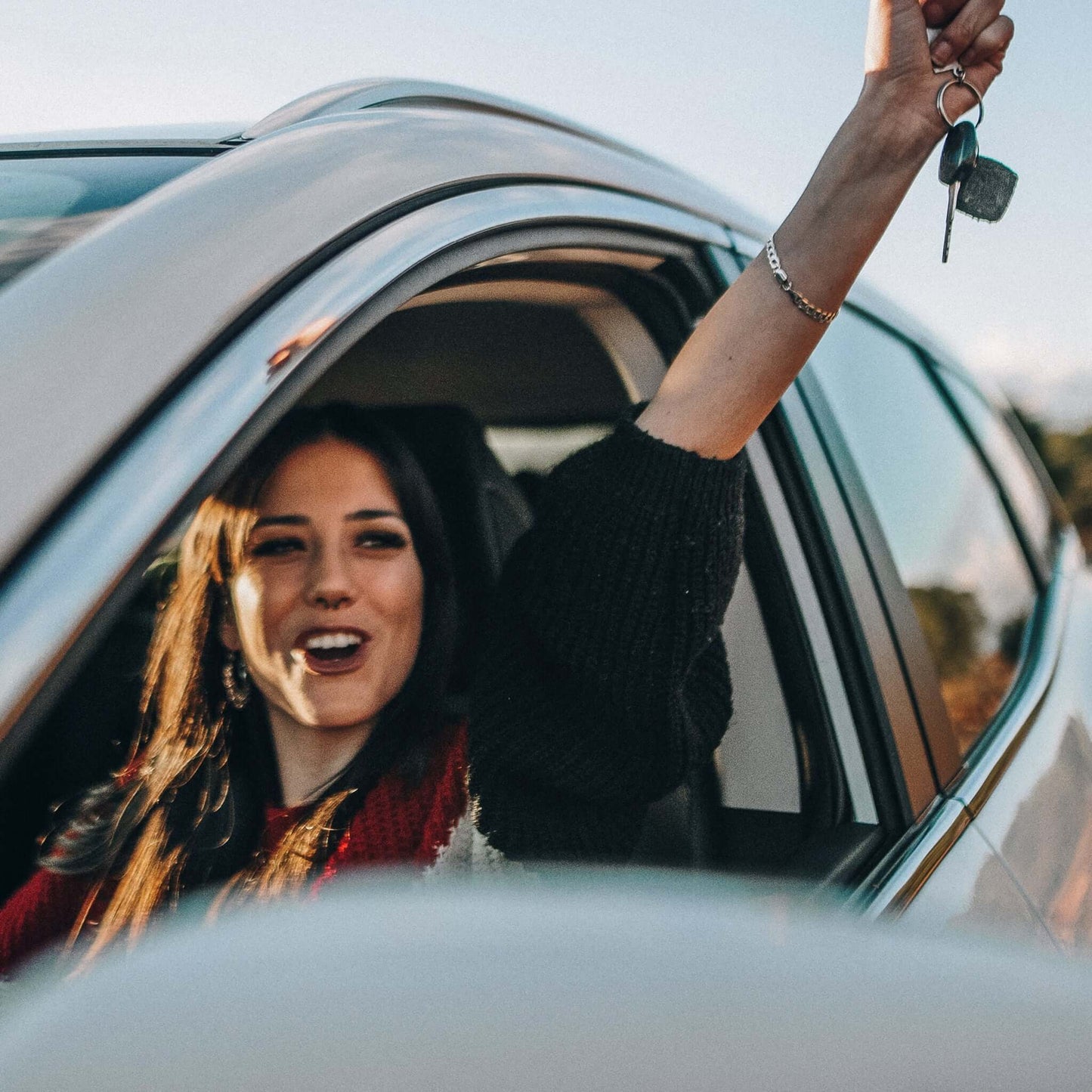 Führerschein übersetzen lassen: Eine junge Frau sitzt am Steuer und freut sich über ihren Führerschein